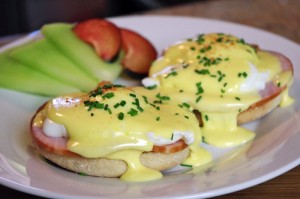Classic eggs Benedict with a side of fruit.